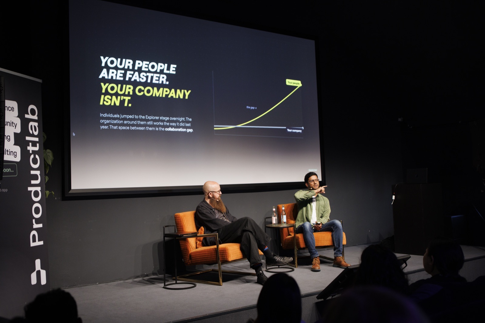 Vihar Parikh on stage at ProductLab Berlin 2026, pointing to a slide that reads: your people are faster, your company isn't.